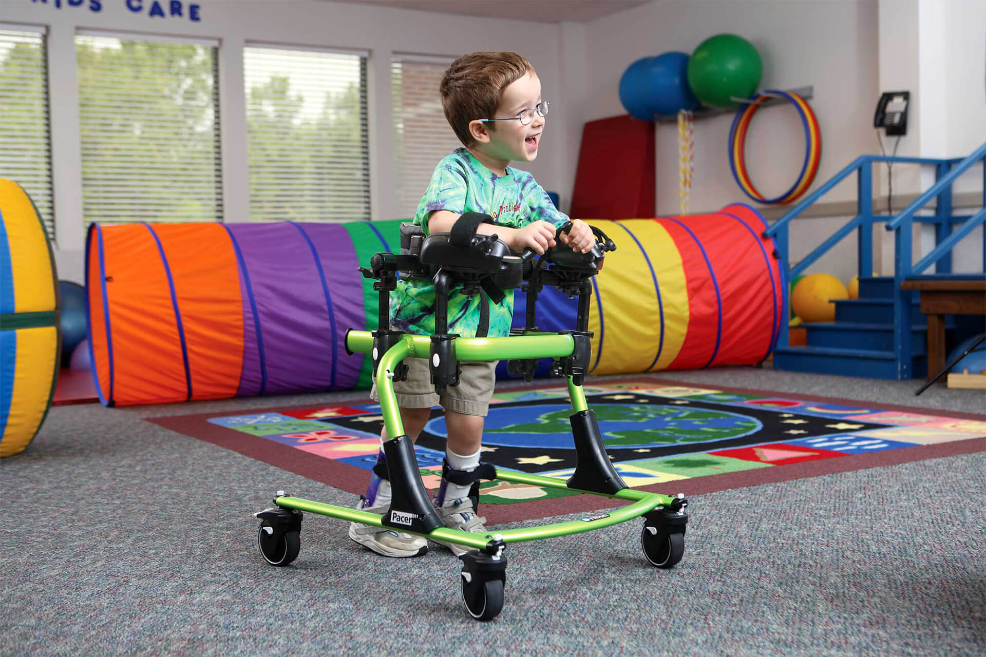 A kid in an adaptive walker in a play room